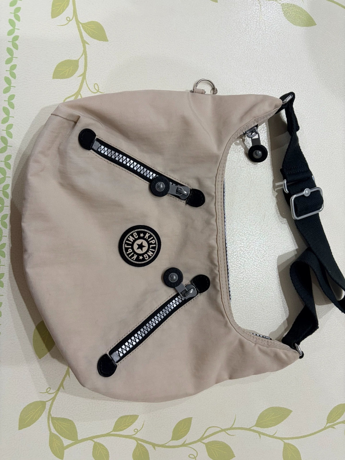 Kipling beige shoulder bag with black strap and front zip pockets