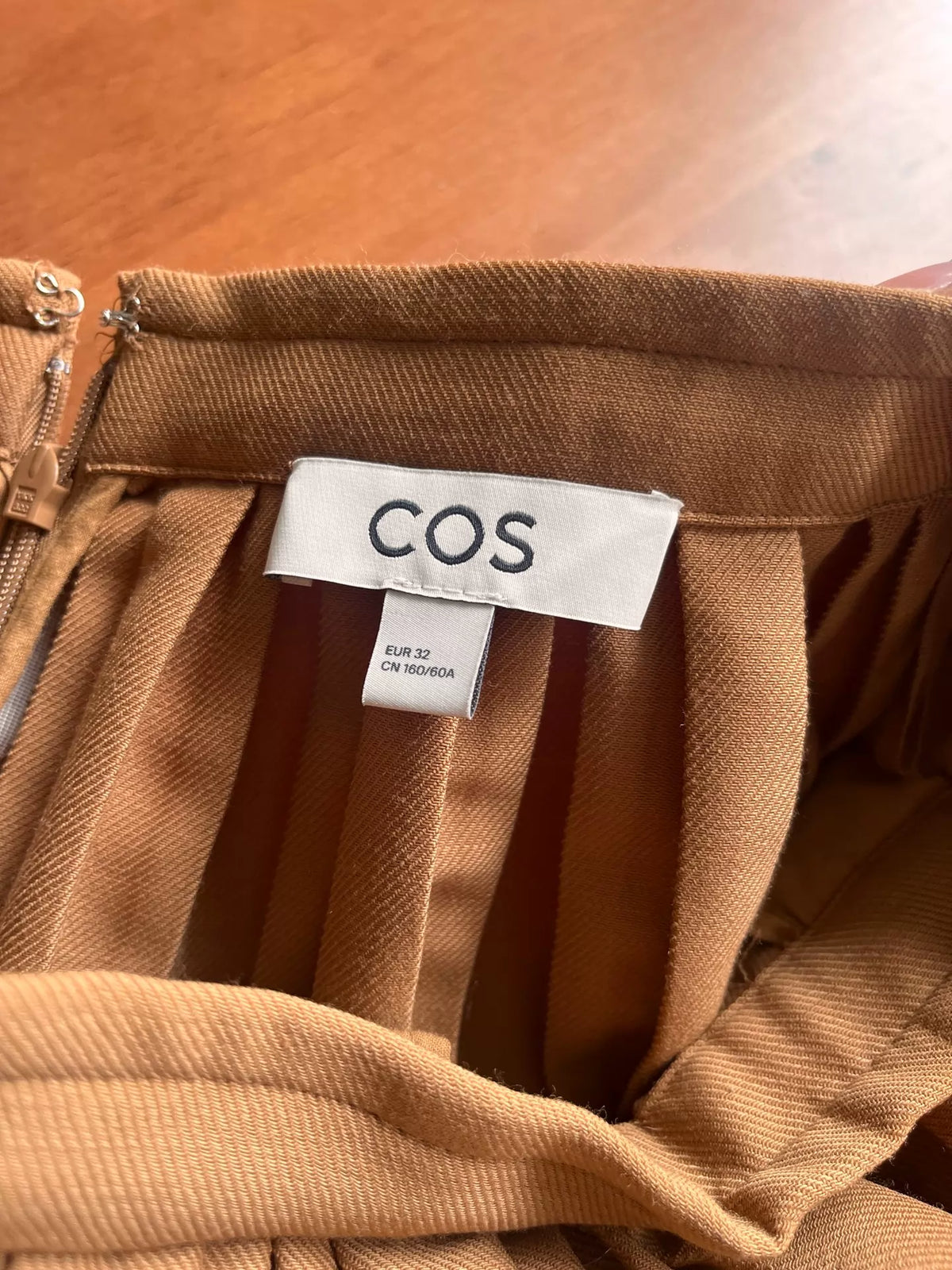 COS EU 32 label and waist closure on caramel pleated skirt